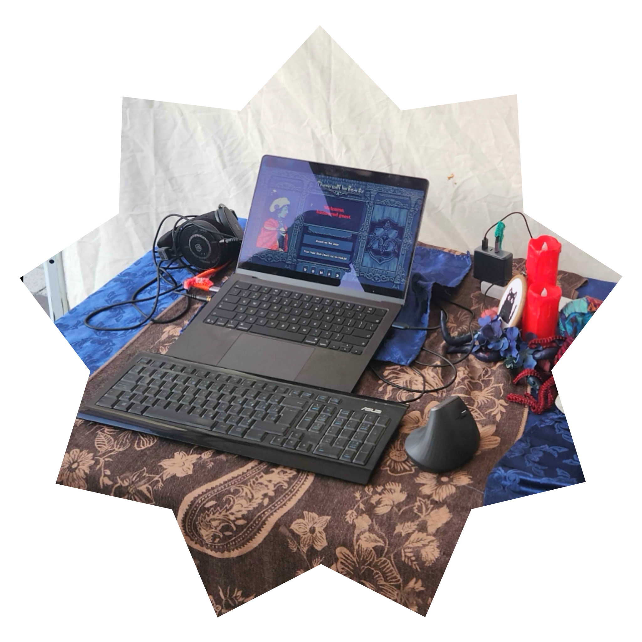 Photo of a laptop and keyboard with red candles and a plastic skull next to it, all on top of a dark blue table cloth